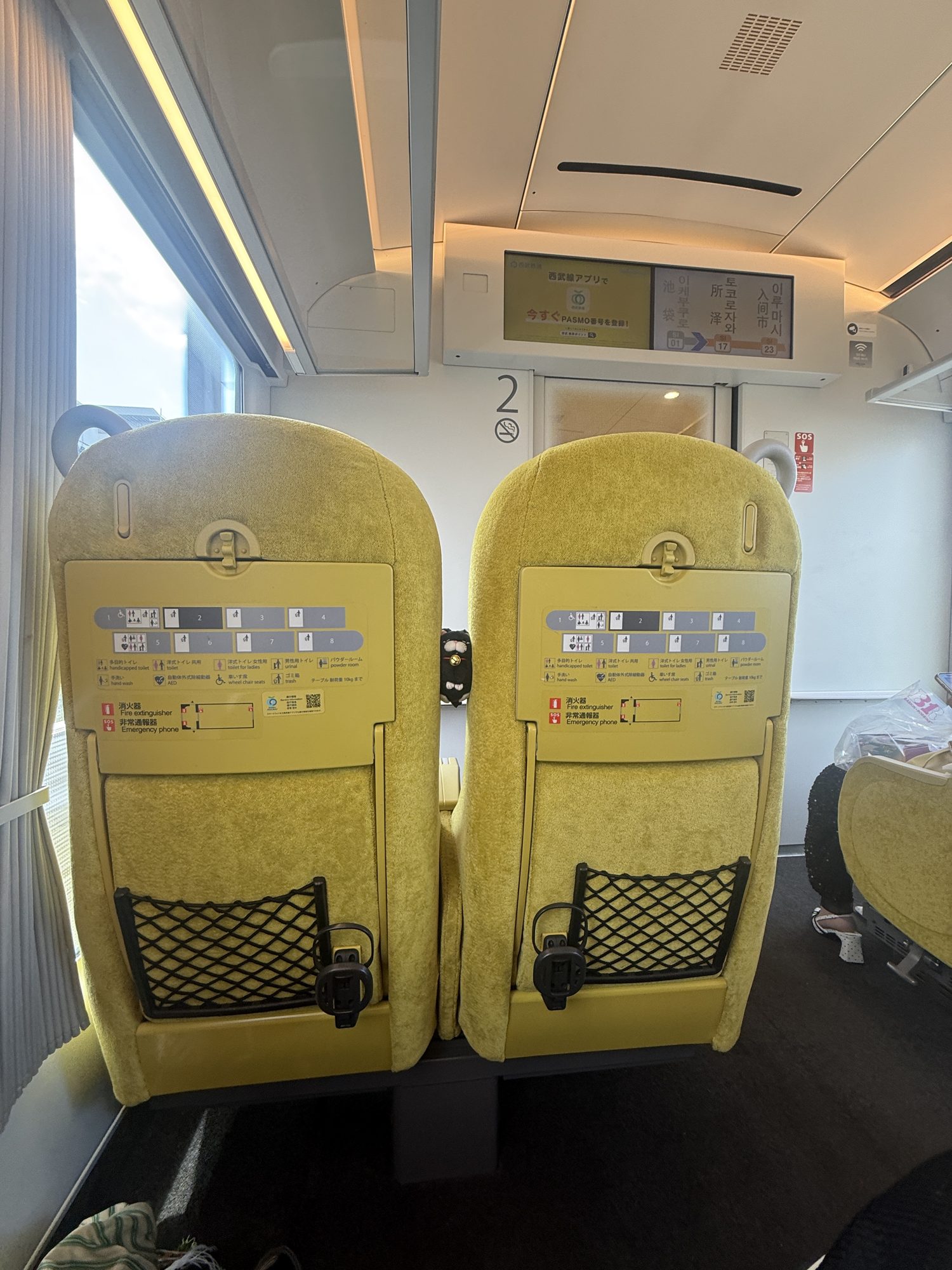 The bright yellow seats of the Laview limited express train, with a route display showing Ikebukuro to Tokorozawa