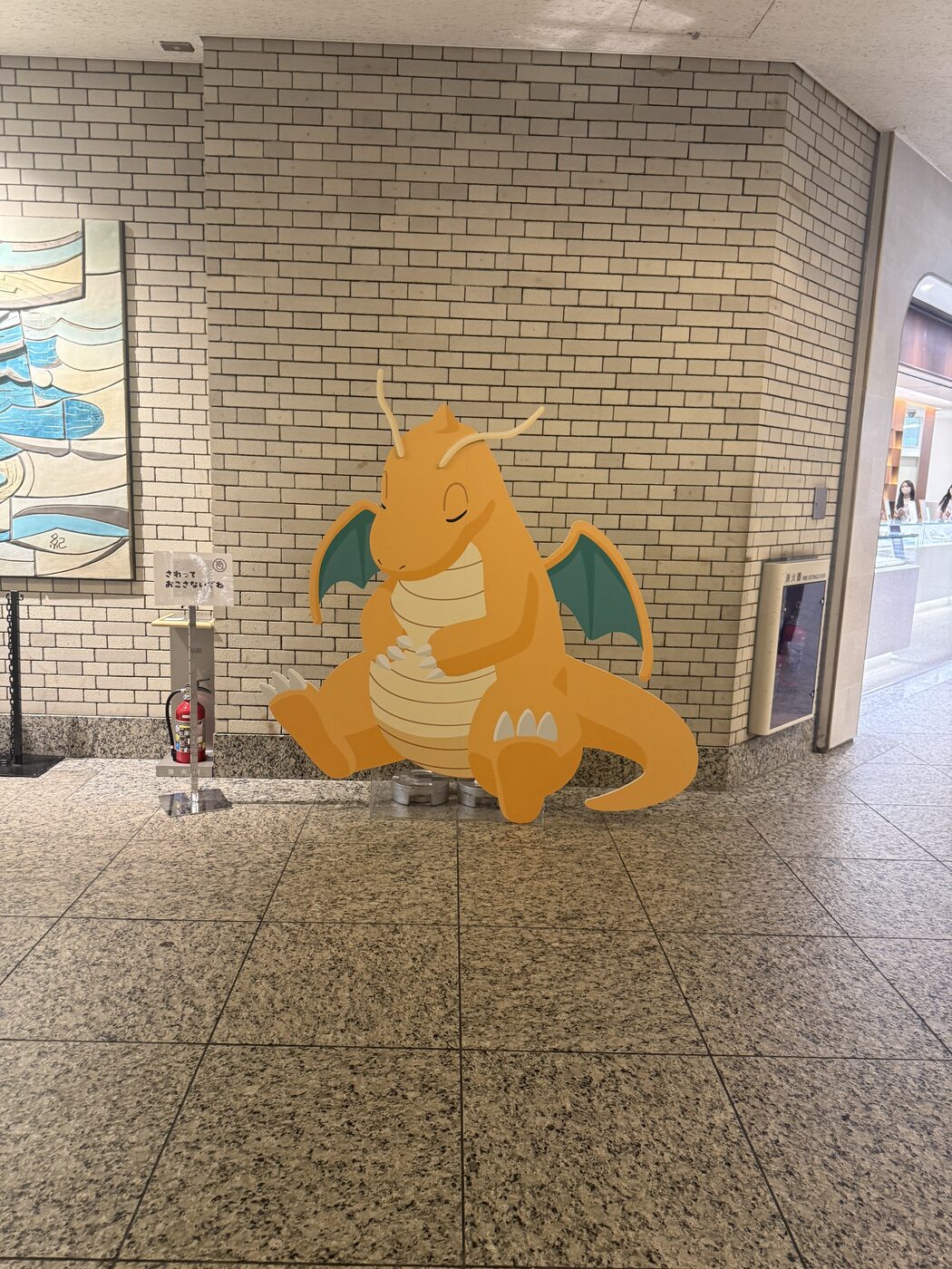 A large Dragonite figure propped up against a tiled wall