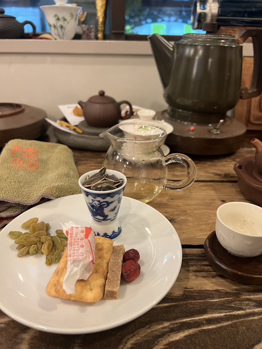 A plate of small nibbles beside the tea: dried fruit, seeds and a cracker