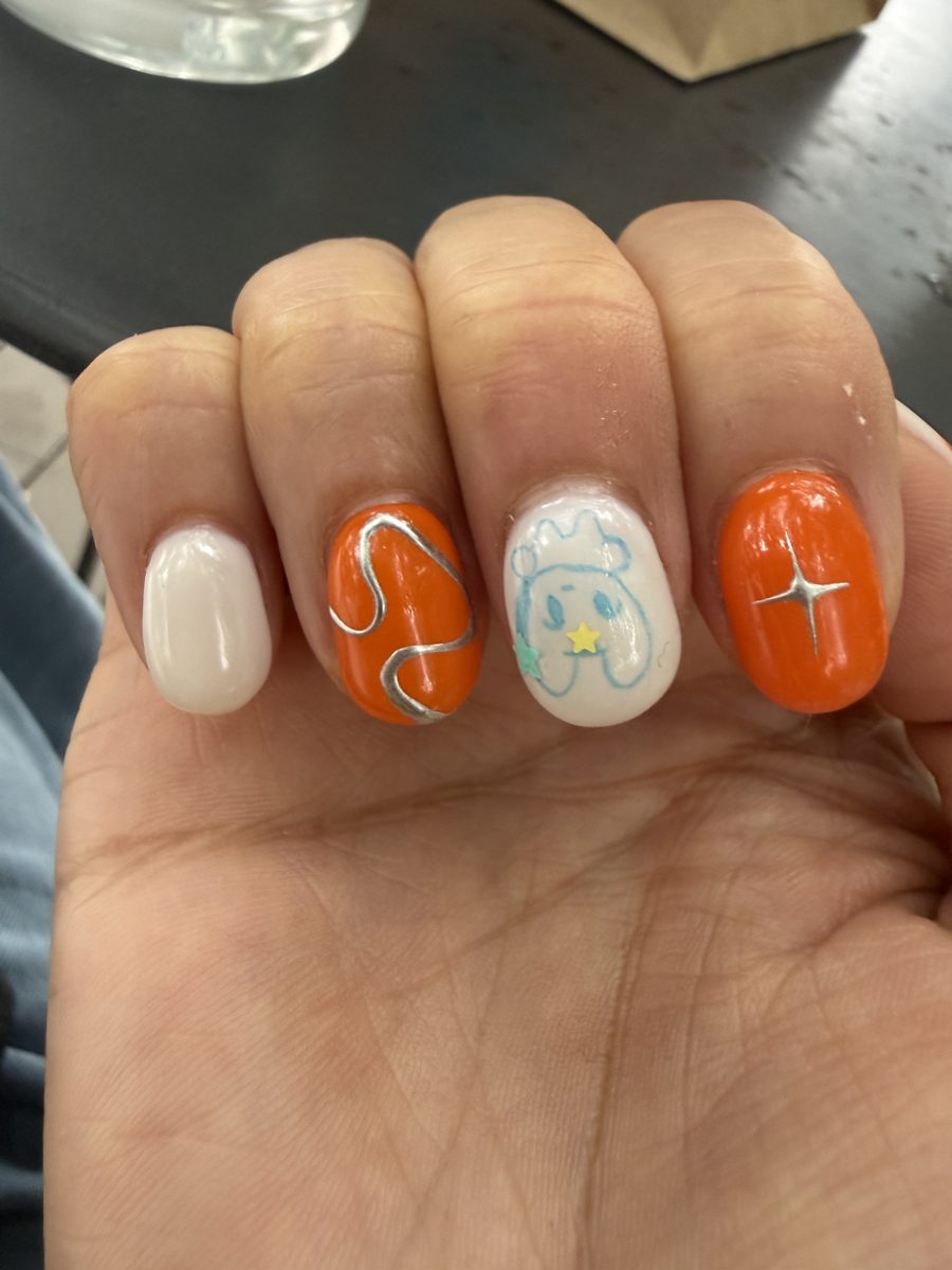 Short round nails in white and orange with silver chrome line art and a four-point star