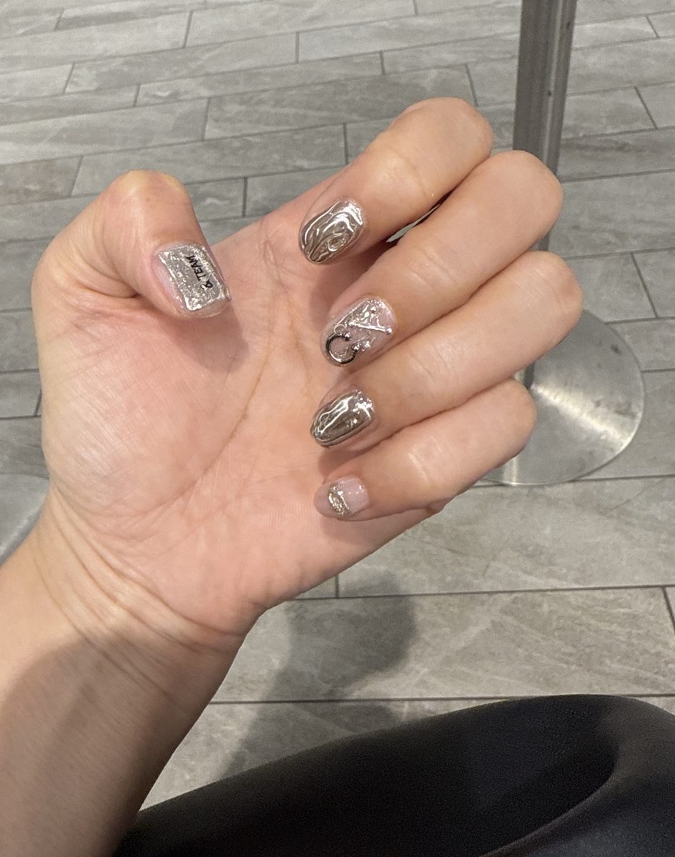 Nails with silver mirror finish, metal charms and a small tag design
